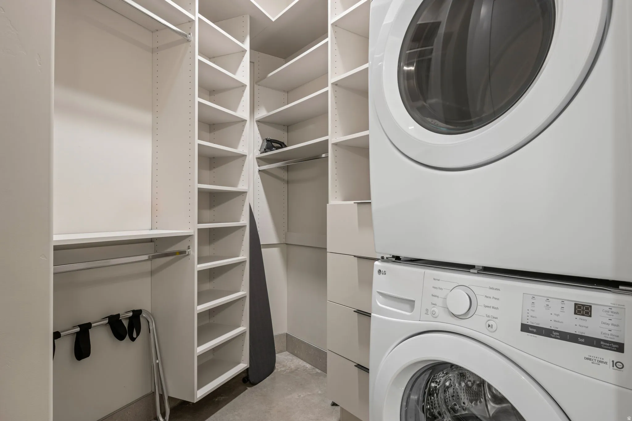 Laundry area with stacked washer and dryer and concrete floors