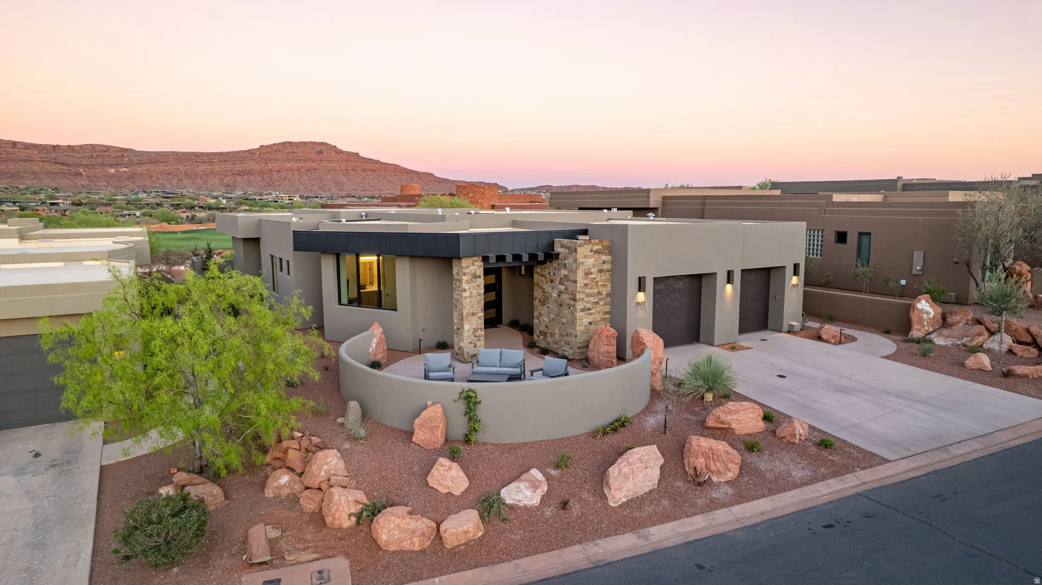 View of front facade featuring stucco siding, driveway, an attached garage, a mountain view, and a patio area