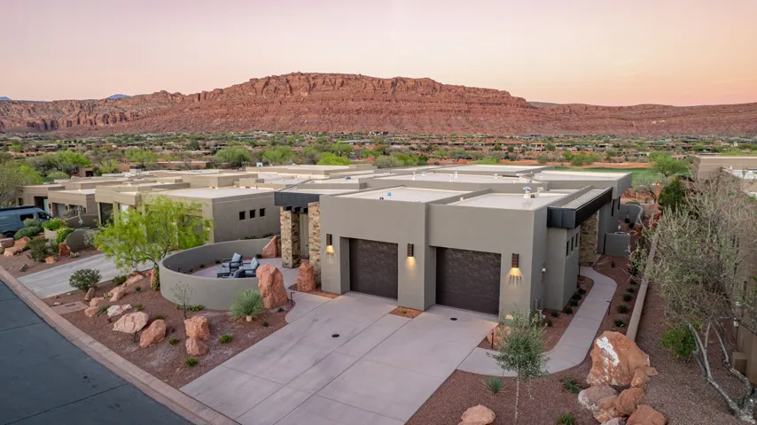 Pueblo-style home featuring a mountain view, stucco siding, driveway, an attached garage, and a residential view