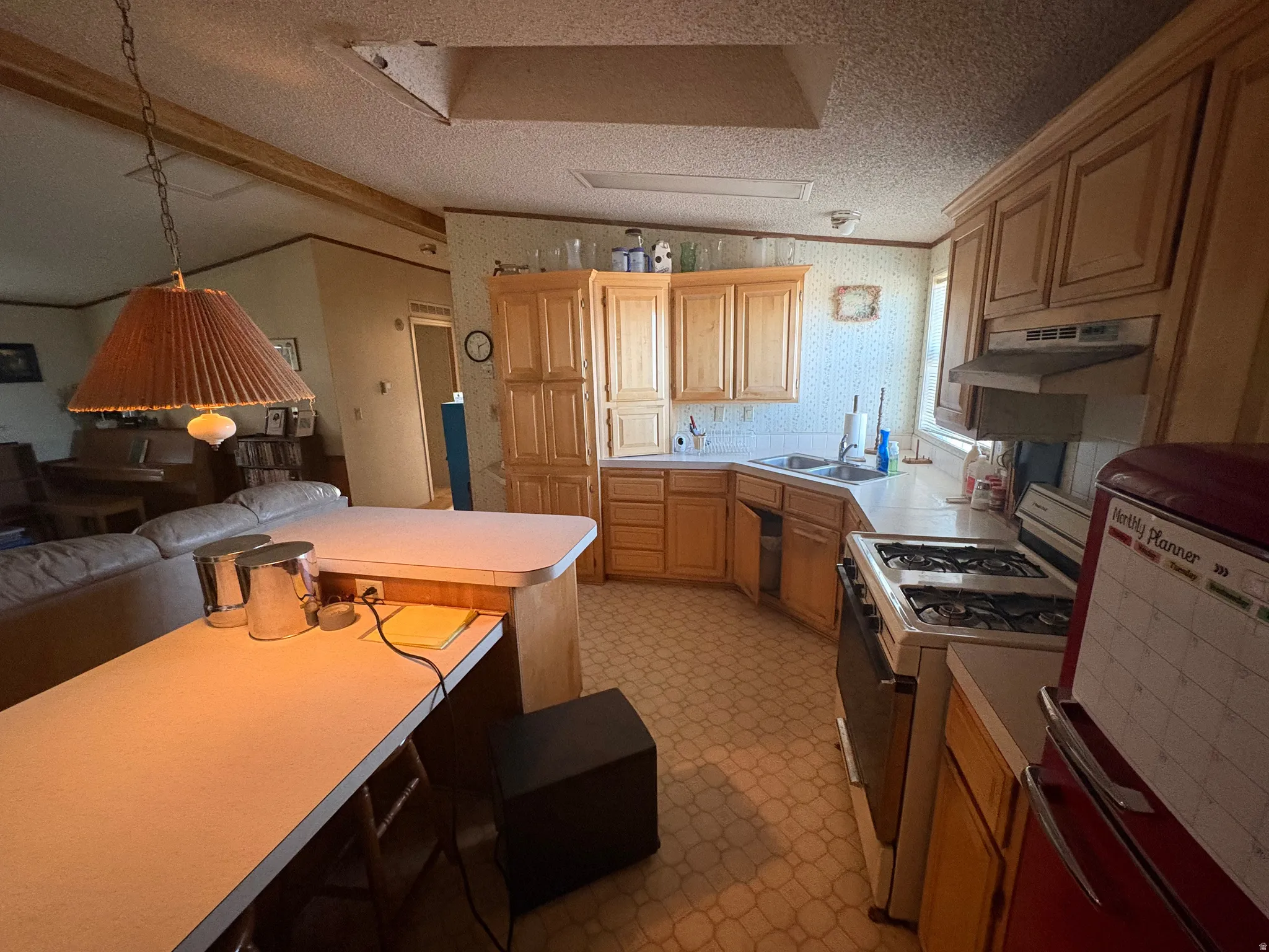 Kitchen featuring gas range gas stove, light countertops, light floors, wallpapered walls, and open floor plan