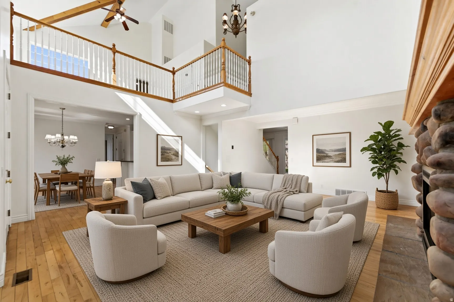 Two-story living area with wood-finish flooring, a stone-clad fireplace, and an open balcony overlooking the space