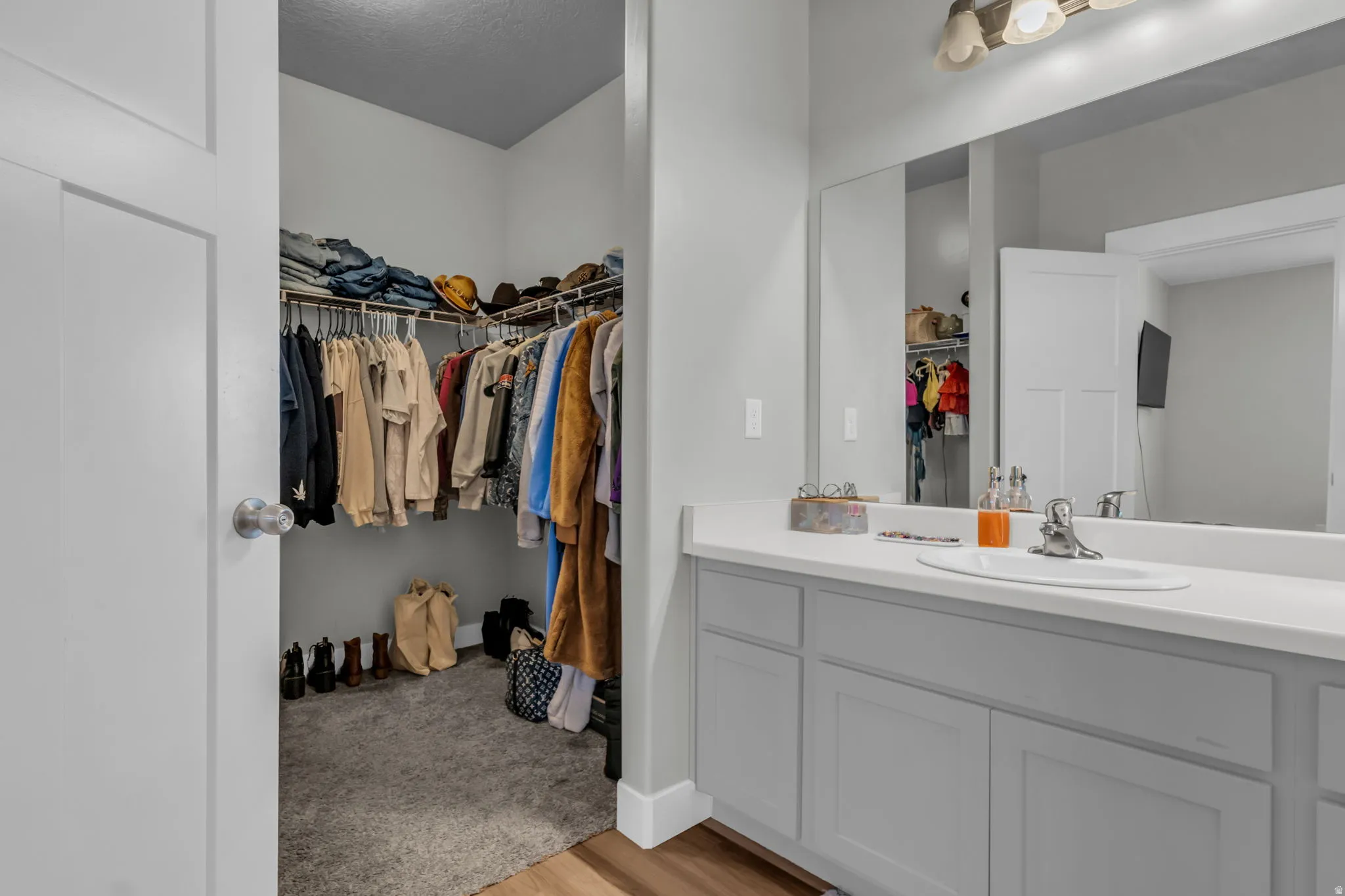 Bathroom featuring a walk in closet, vanity, and light wood finished floors