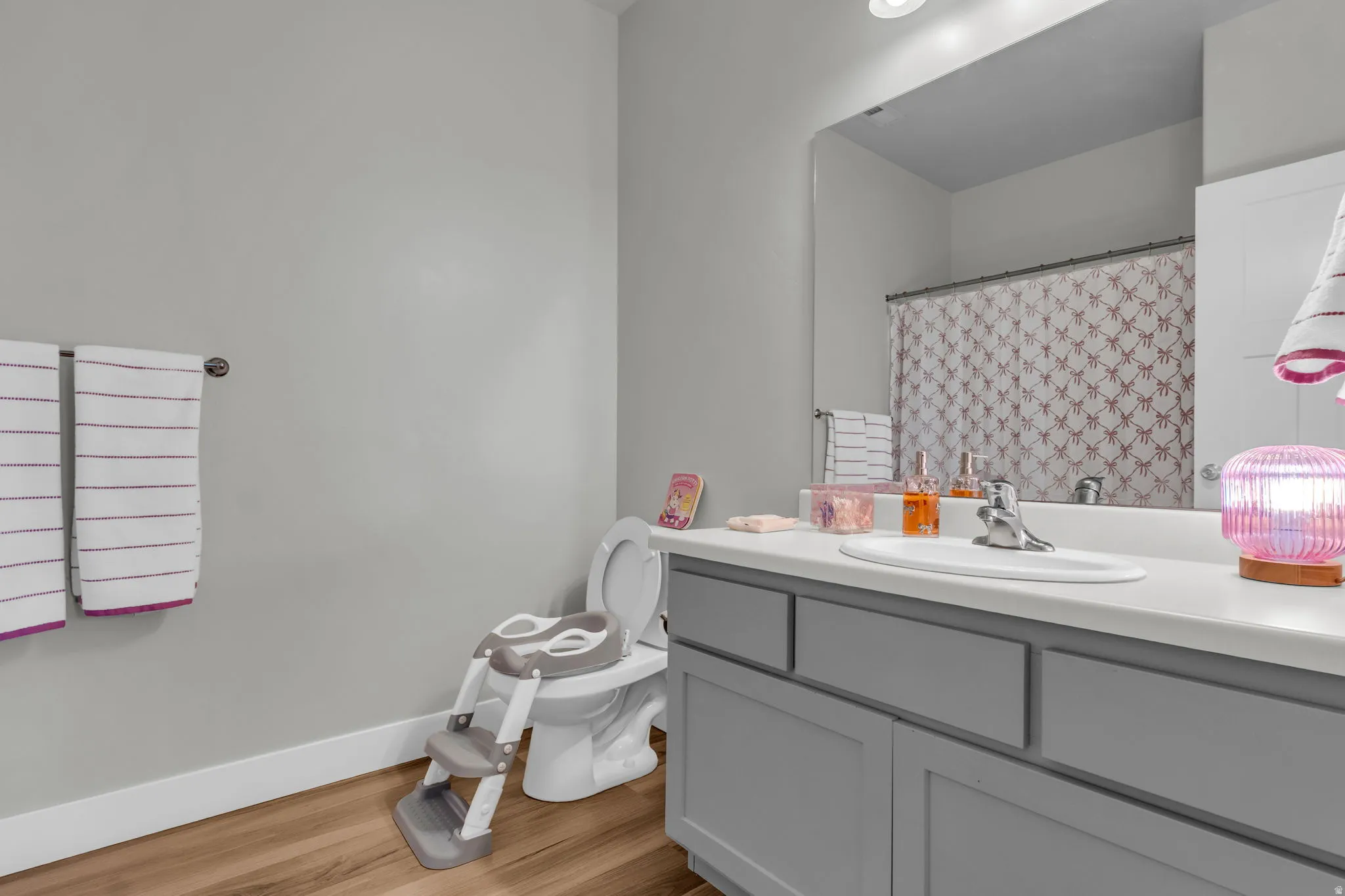 Full bath with vanity, light wood-type flooring, and a shower with curtain