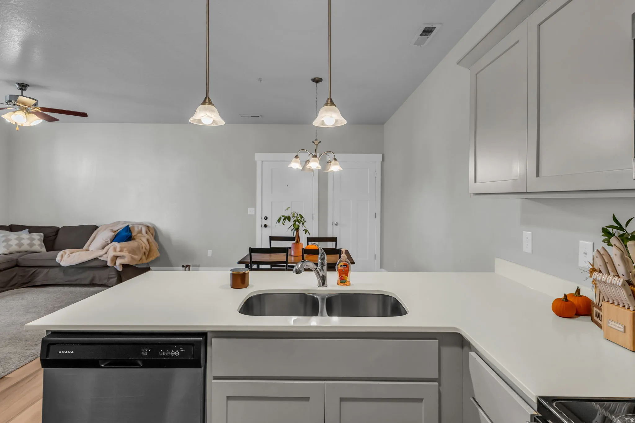 Kitchen featuring a peninsula, open floor plan, stainless steel dishwasher, ceiling fan, and black stove