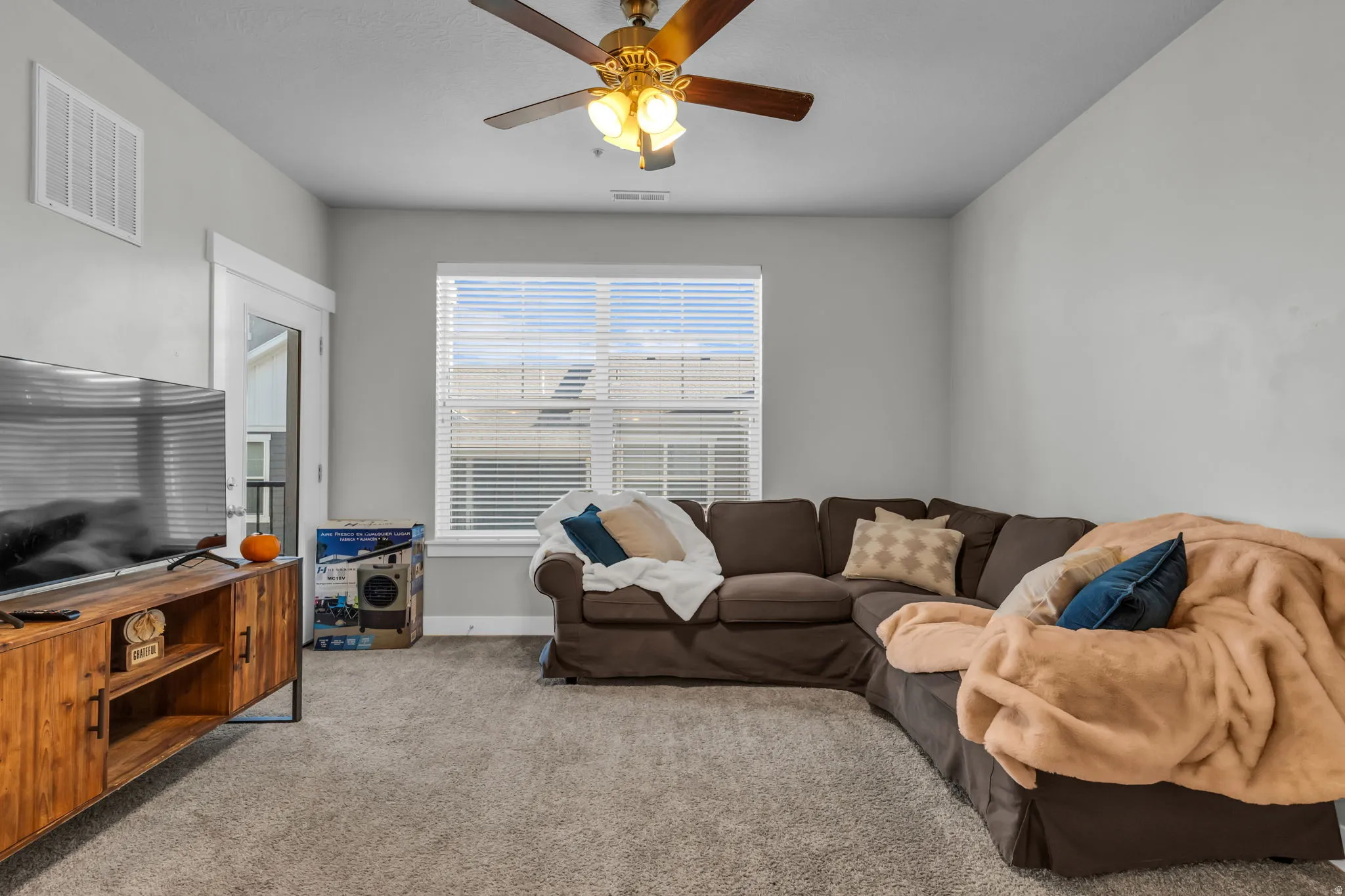 Carpeted living room with a ceiling fan and baseboards