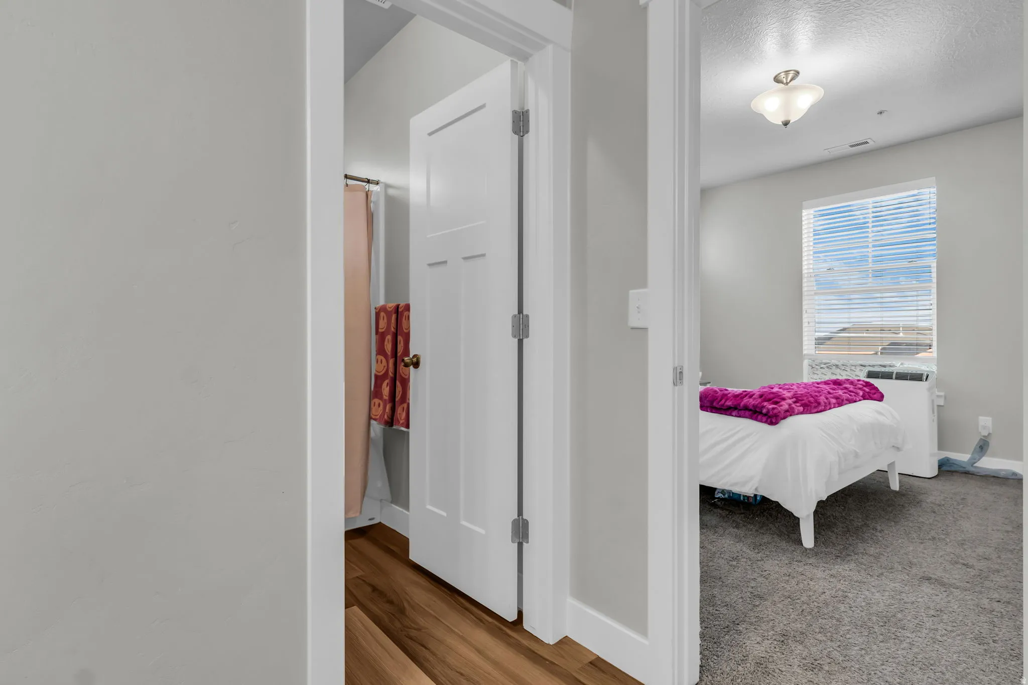 Corridor featuring a textured ceiling, light wood-style flooring, and light carpet