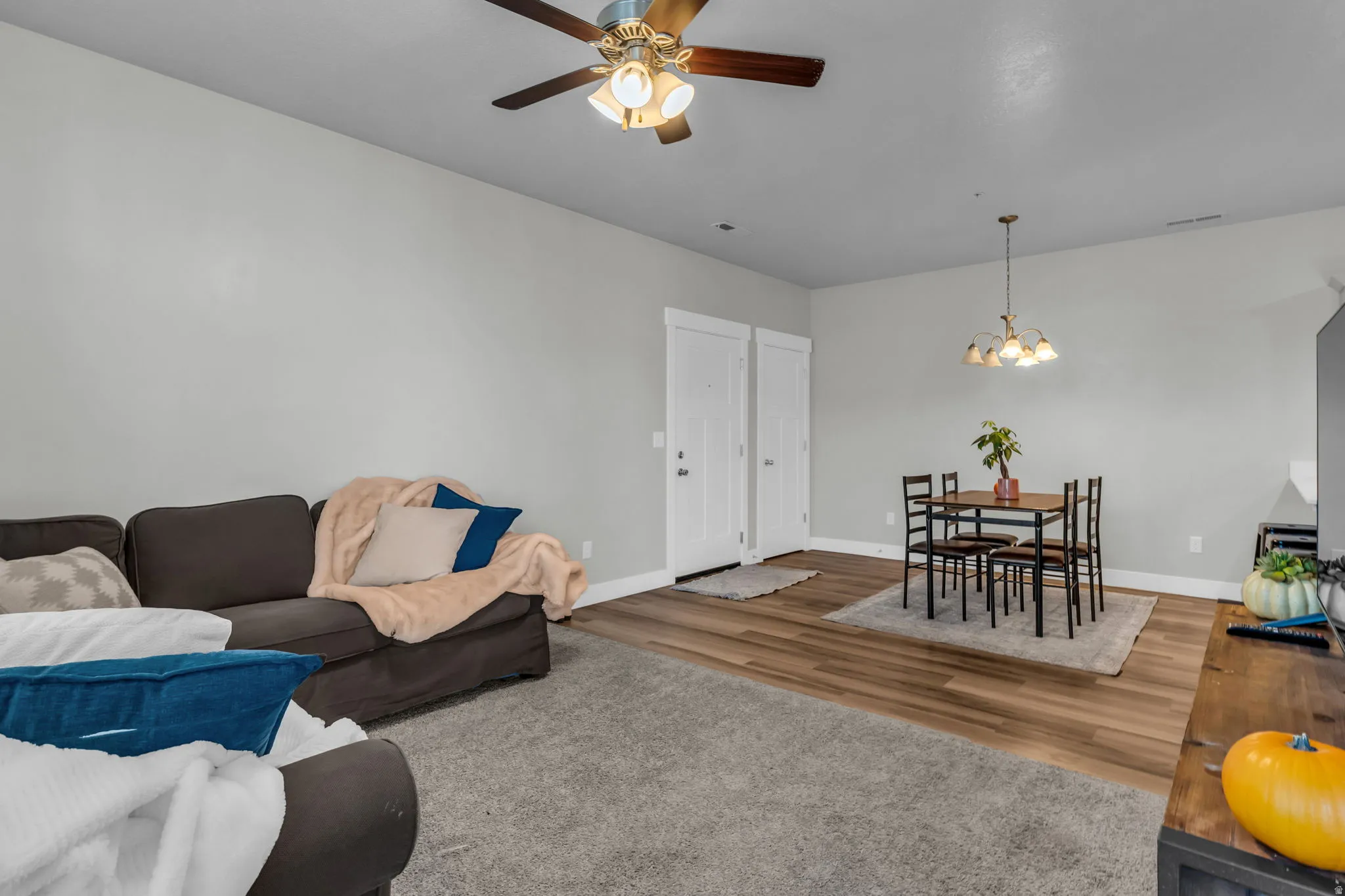Living room featuring ceiling fan, hanging lights, and wood finished floors