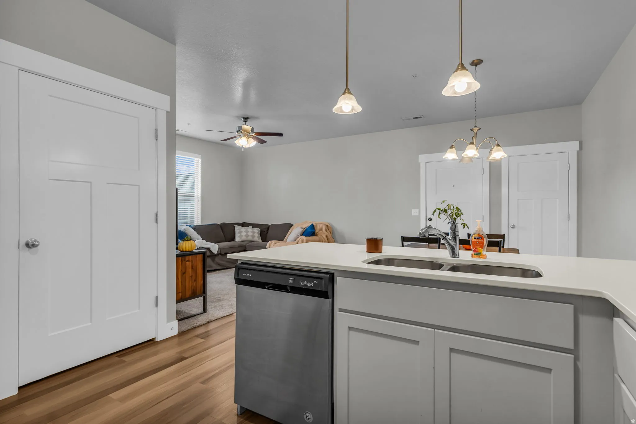 Kitchen featuring dishwasher, open floor plan, light stone countertops, hanging lights, and dark wood-style flooring