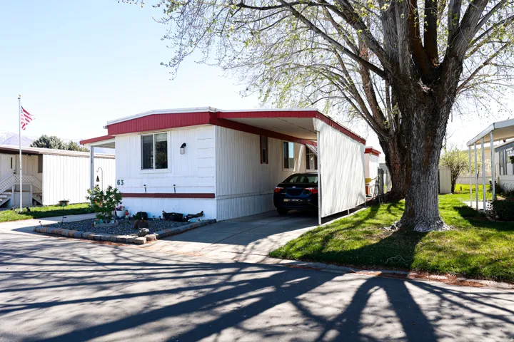 Manufactured / mobile home featuring a carport, a front yard, and concrete driveway