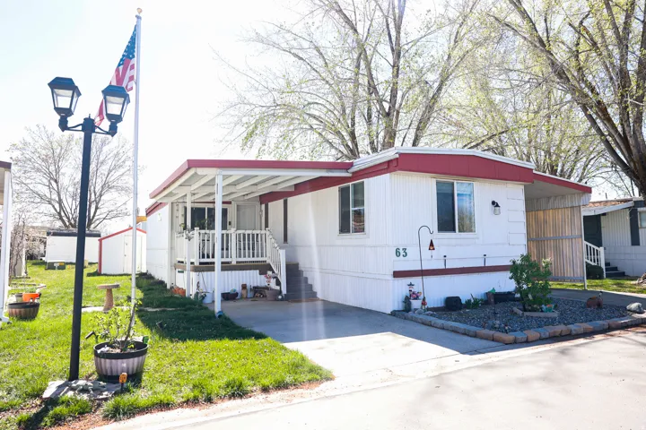 Manufactured / mobile home featuring a front lawn, an attached carport, and concrete driveway