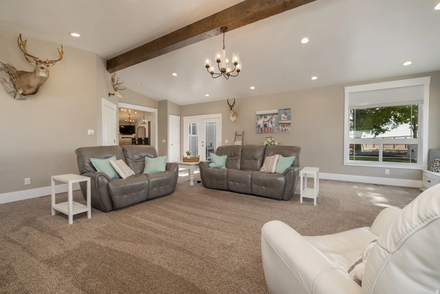 Living area with vaulted ceiling with beams, carpet floors, and a chandelier