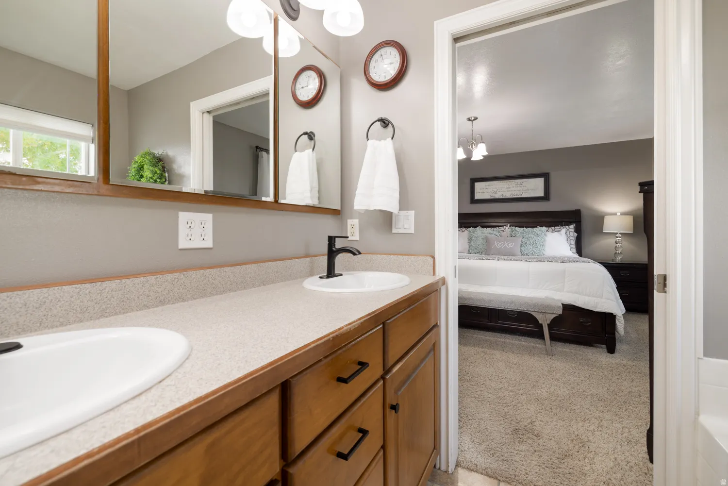 Bathroom featuring double vanity, light carpet, and ensuite bath