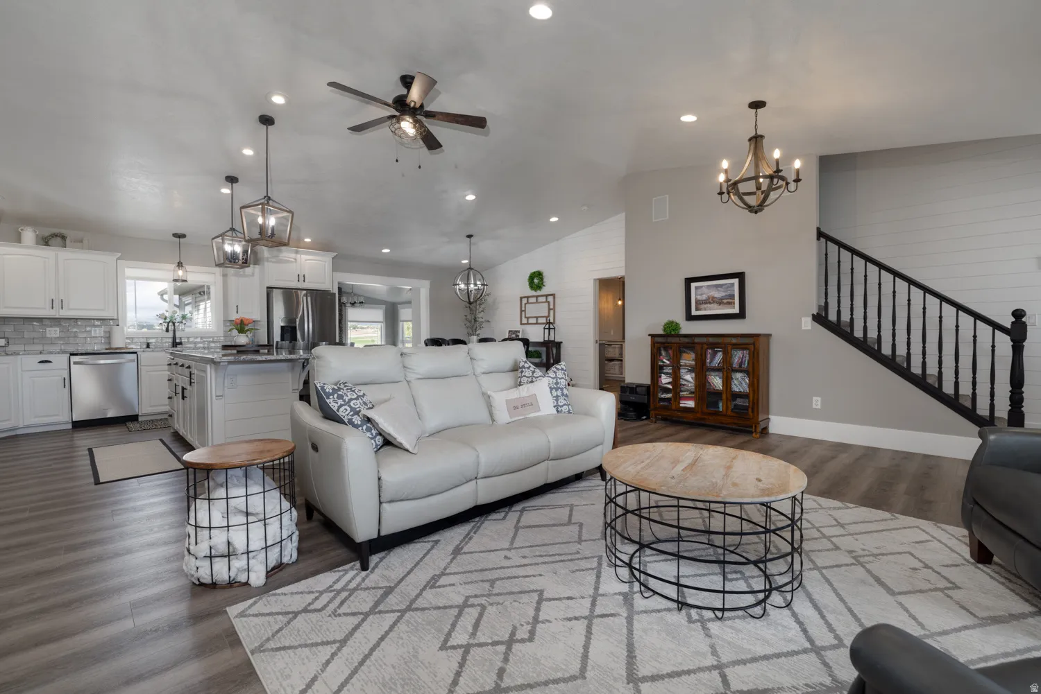 Living room featuring a chandelier, dark wood finished floors, a ceiling fan, and lofted ceiling