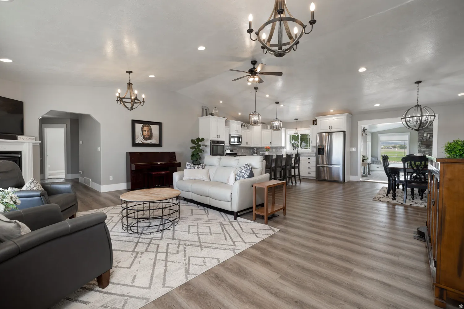 Living area featuring hanging lights, light wood-type flooring, a fireplace, and a ceiling fan