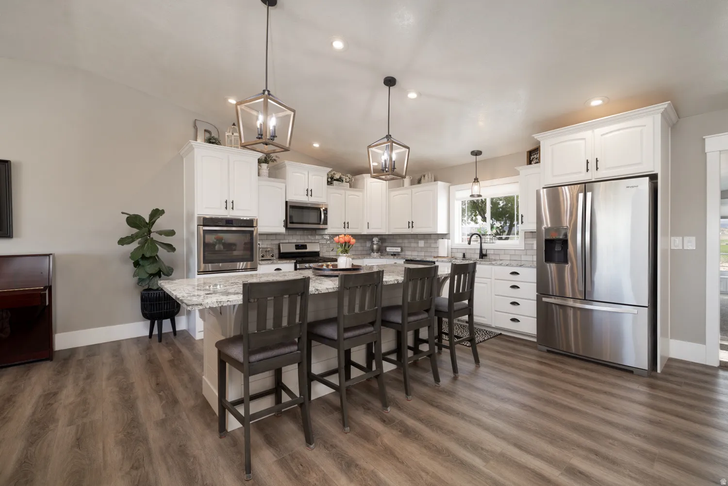 Kitchen with stainless steel appliances, light stone counters, a center island, a breakfast bar area, and white cabinetry