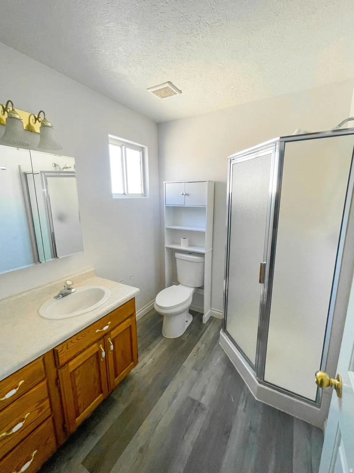 Bathroom with a shower stall, dark wood-style floors, vanity