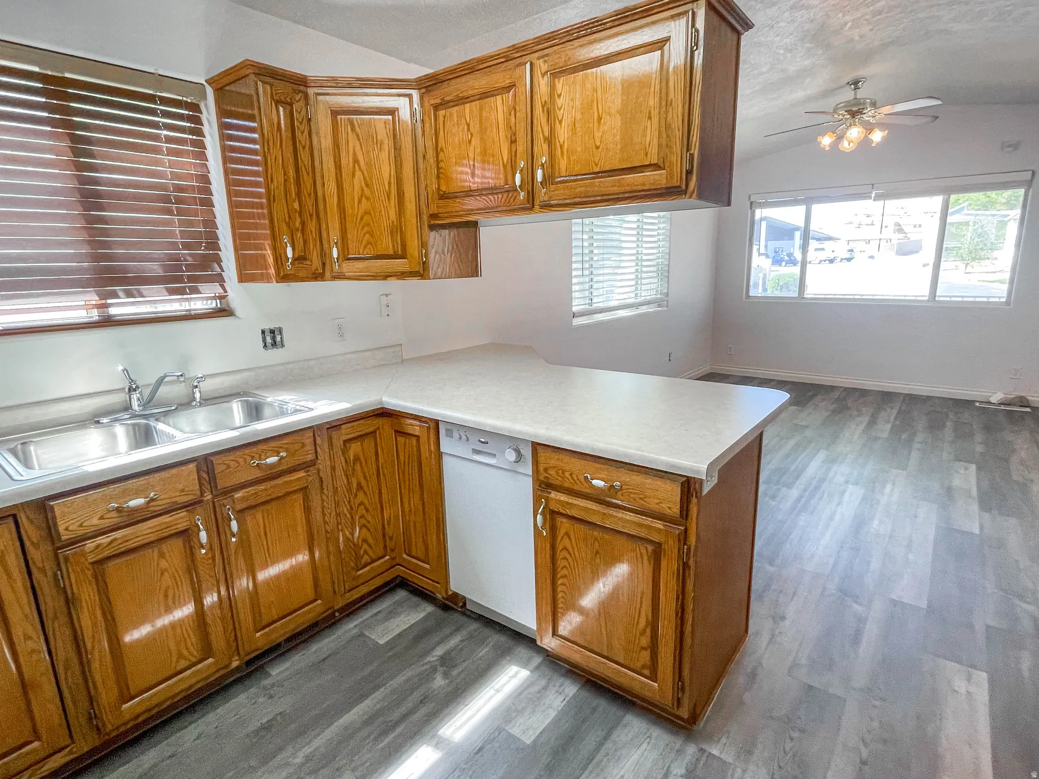 Kitchen featuring a peninsula, light countertops, wood finish cabinets, ceiling fan, and dark wood finished floors