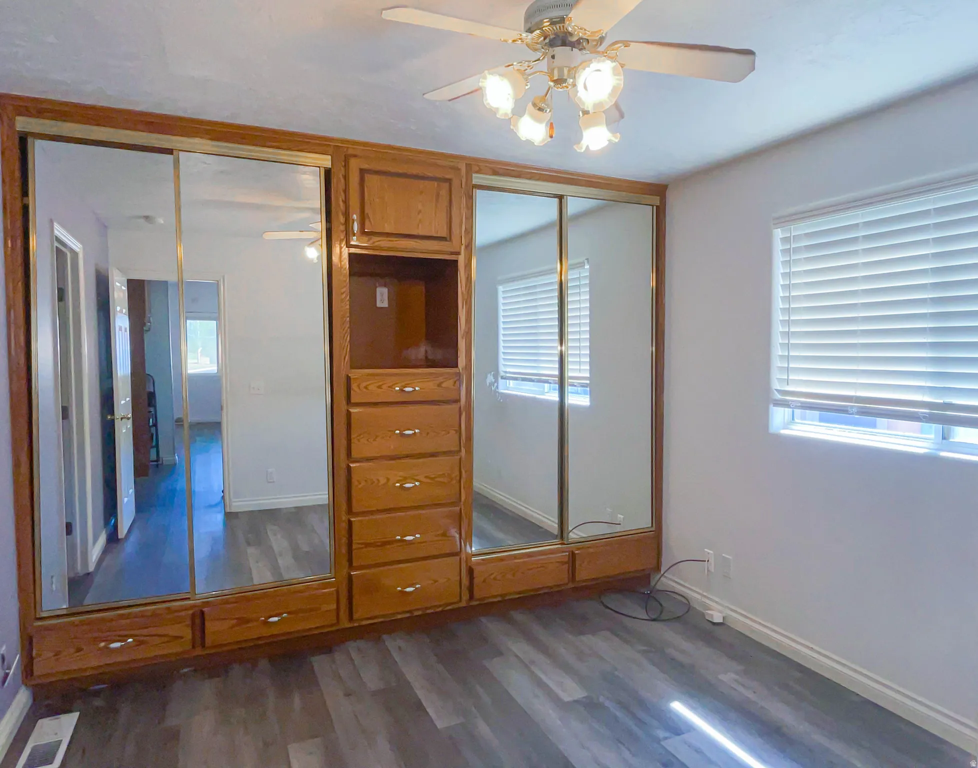 Bedroom with wood finished floors, ceiling fan, and delux closets