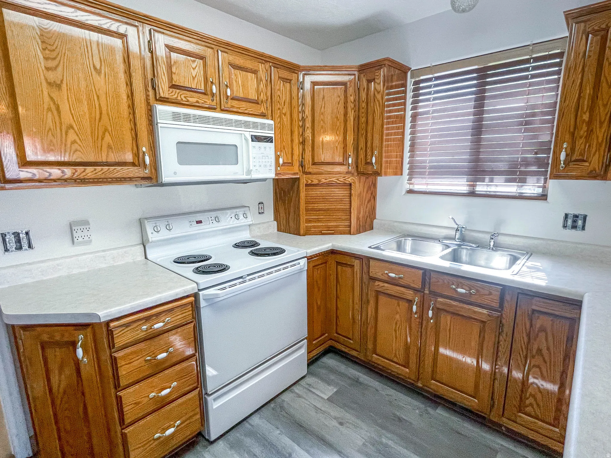 Kitchen featuring white appliances, dark wood-style floors, light countertops, and wood finish cabinetry