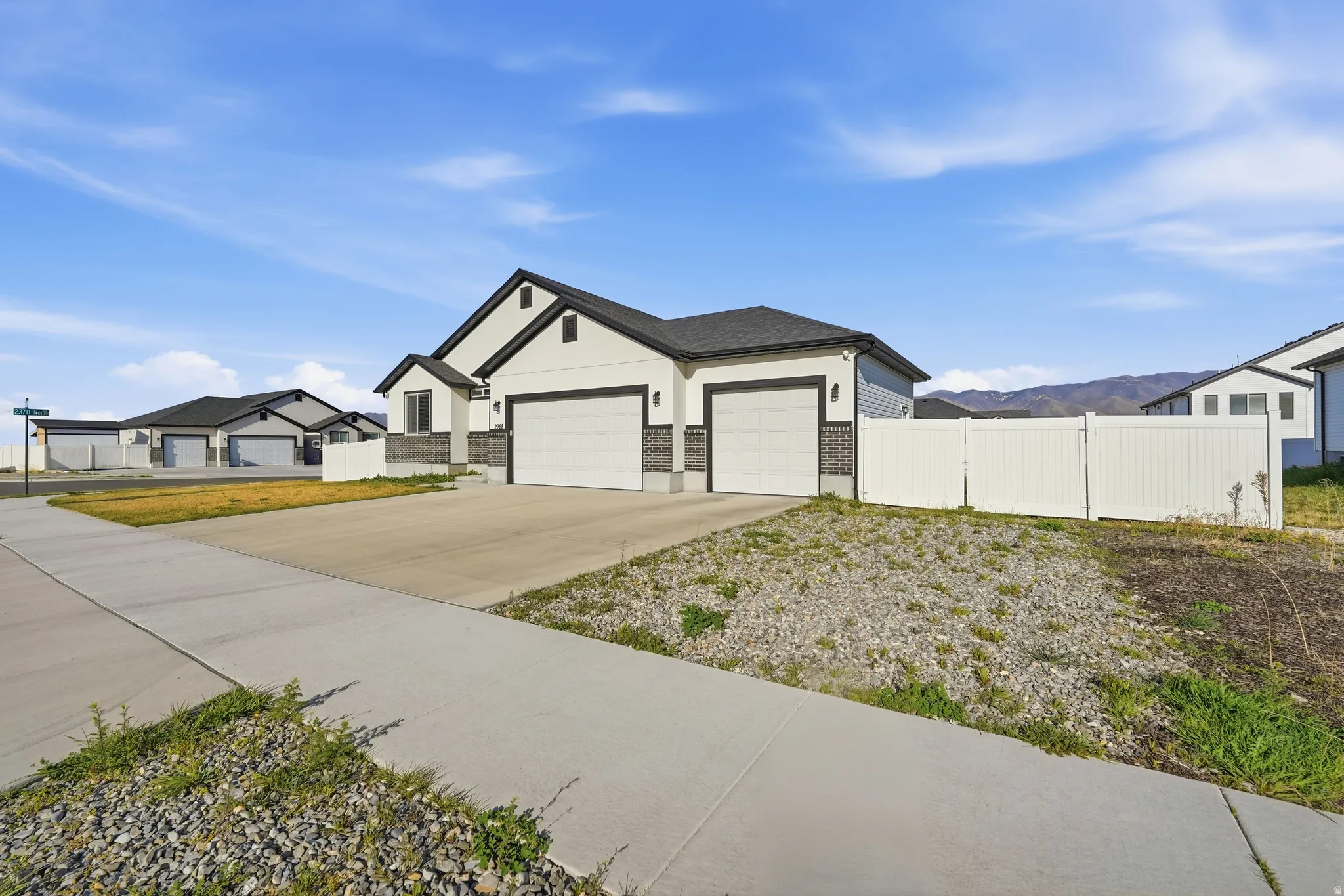 View of front of house featuring brick siding, a gate, an attached garage, driveway, and a mountain view