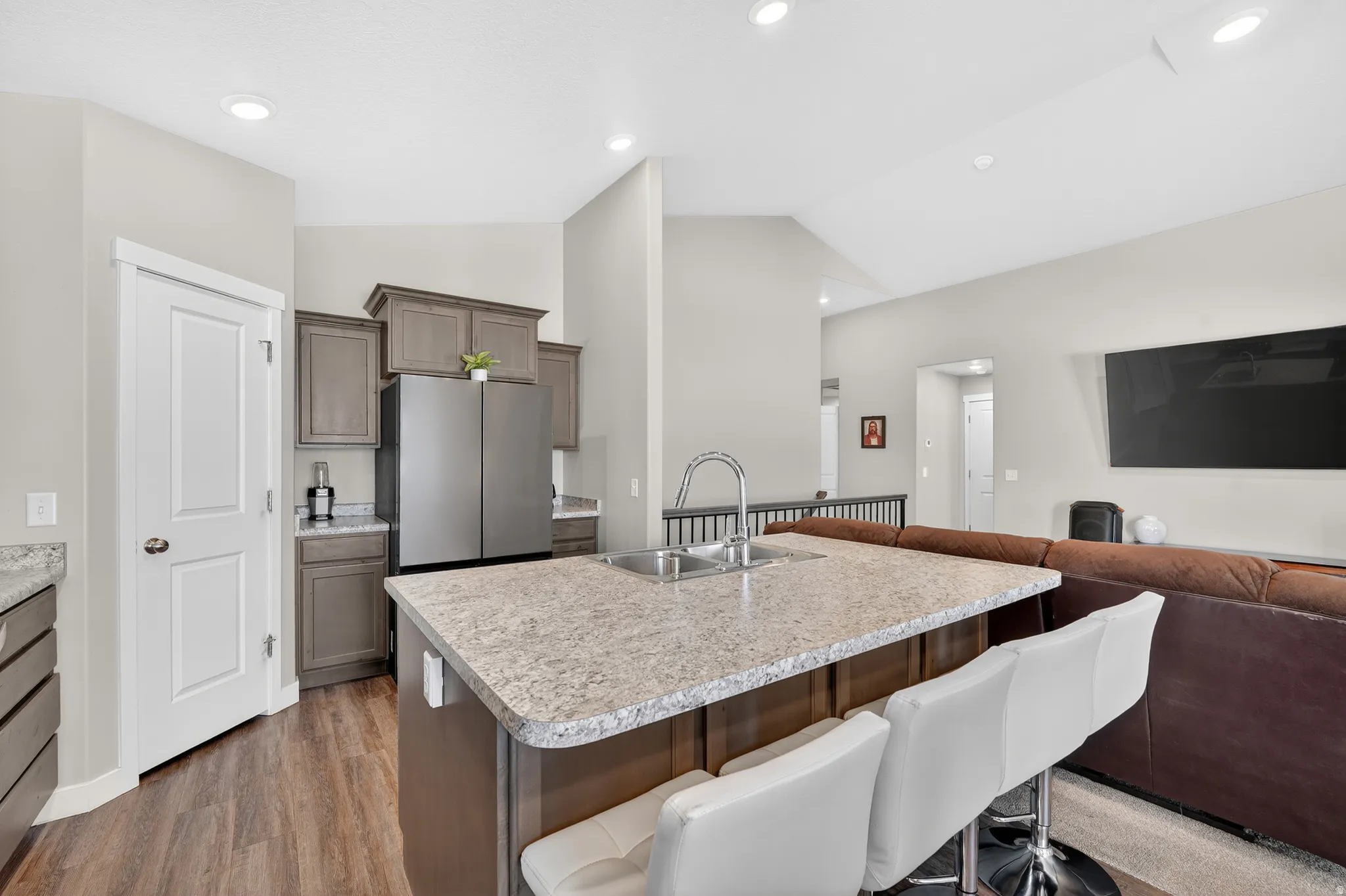 Kitchen with a breakfast bar, a center island with sink, open floor plan, light countertops, and dark wood finished floors