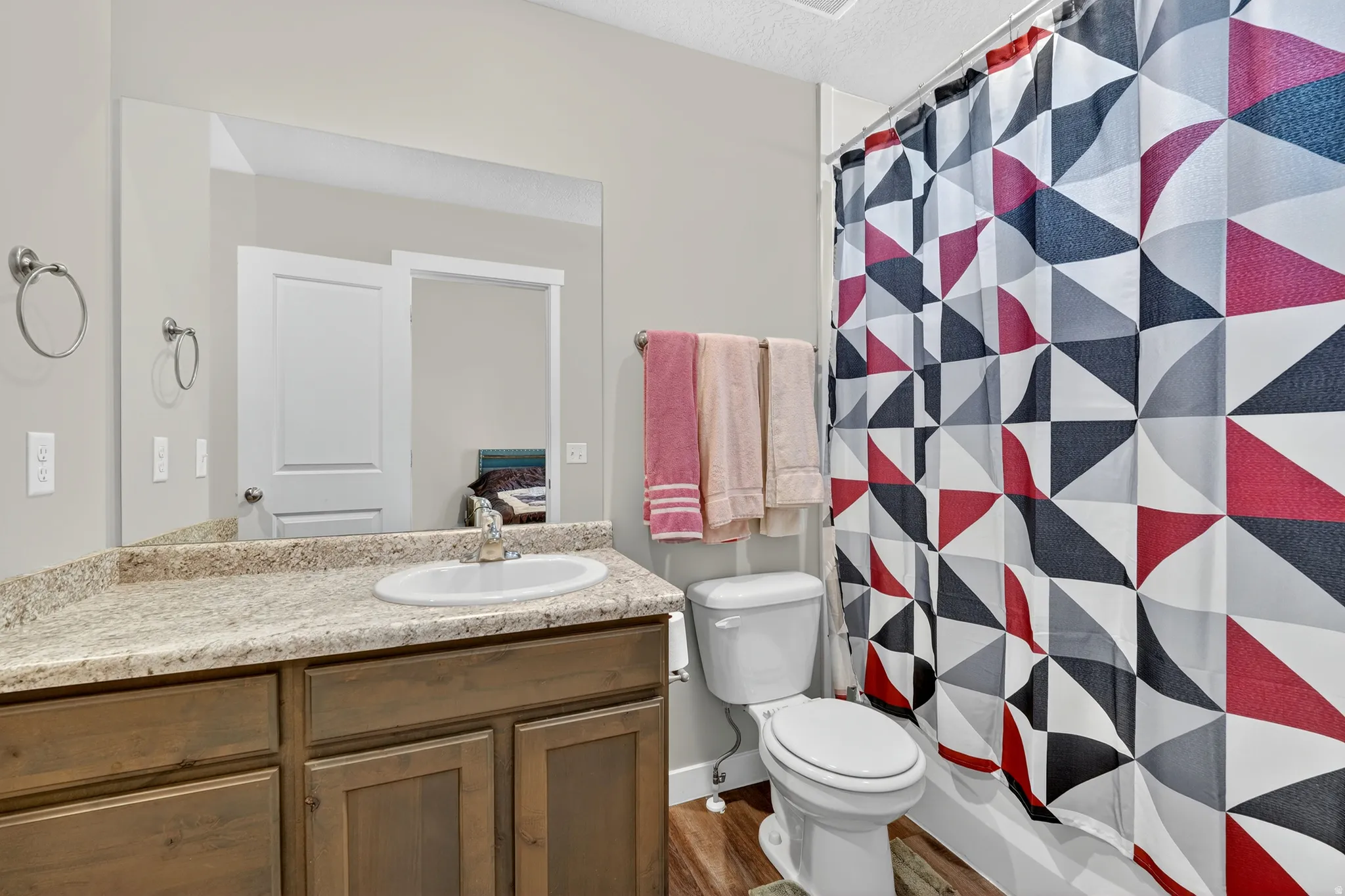 Bathroom with vanity, curtained shower, dark wood-style flooring, and a textured ceiling
