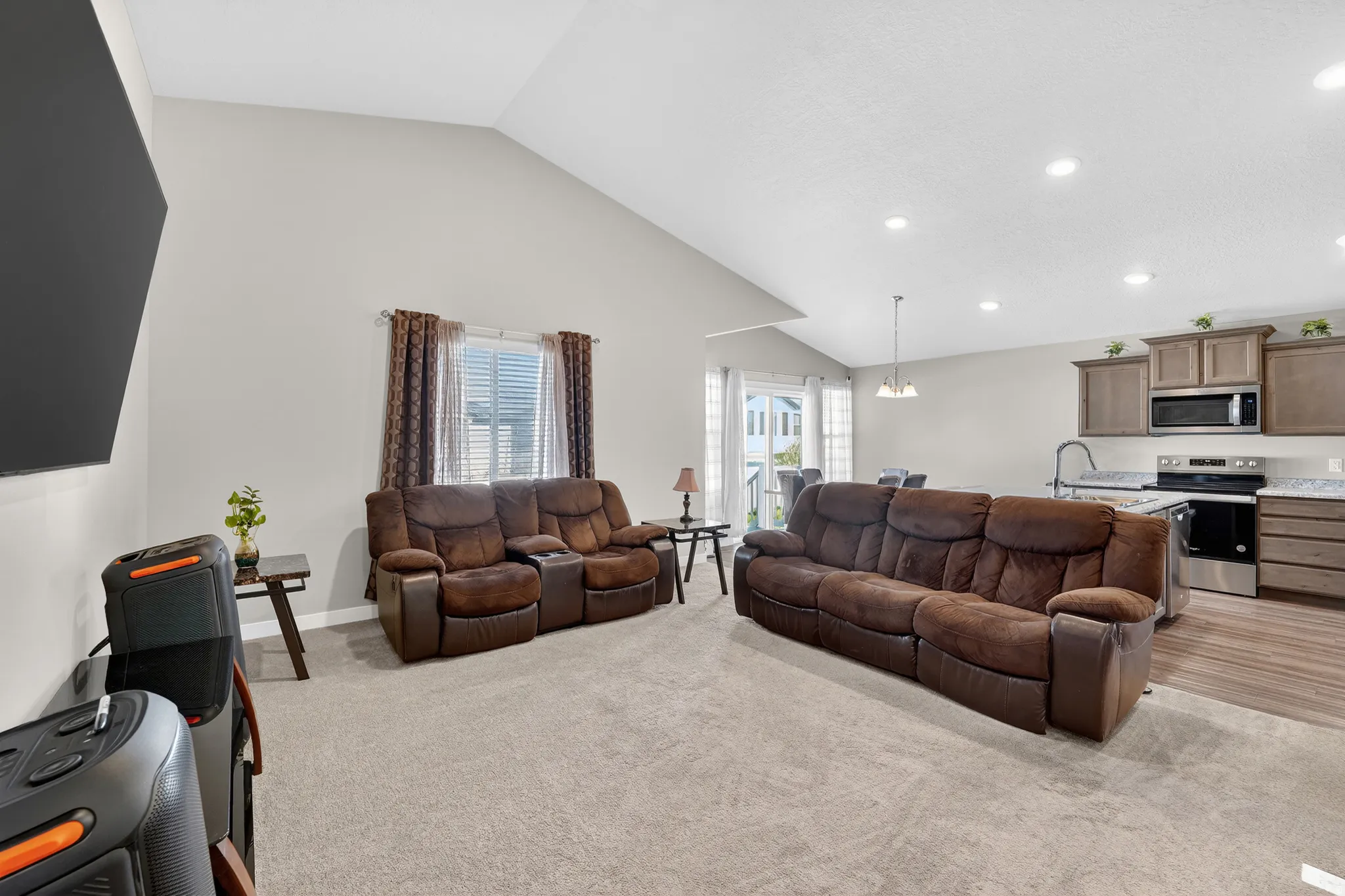 Living room with vaulted ceiling, light colored carpet, and recessed lighting