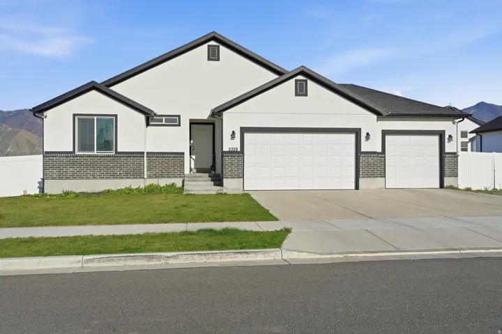 View of front facade featuring an attached garage, a mountain view, concrete driveway, stucco siding, and brick siding