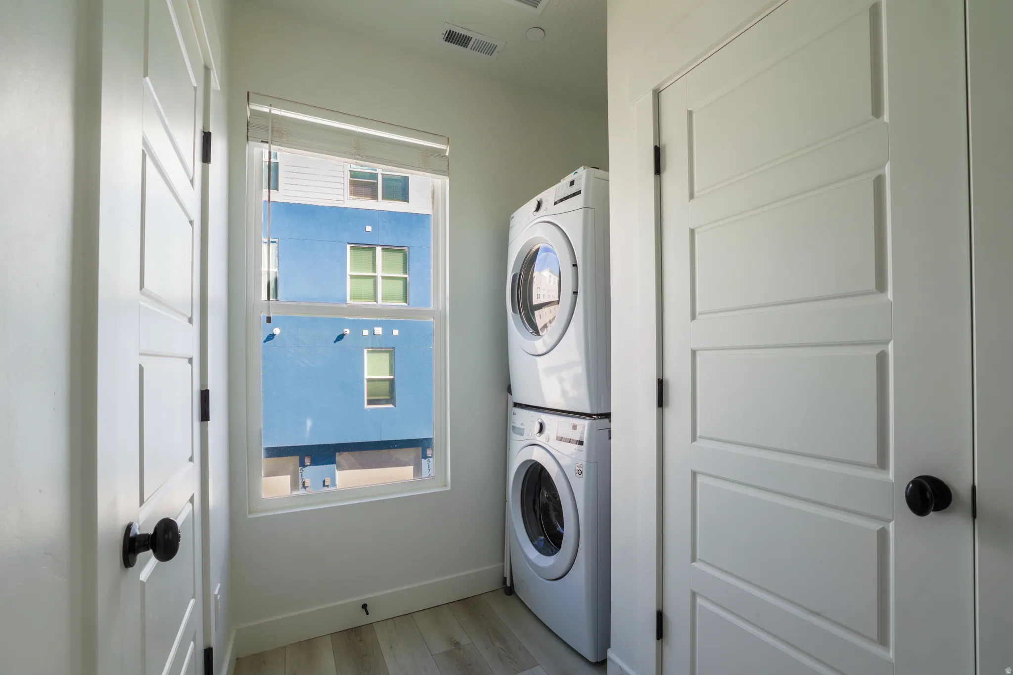 Laundry area featuring light wood-style floors and stacked washer and clothes dryer