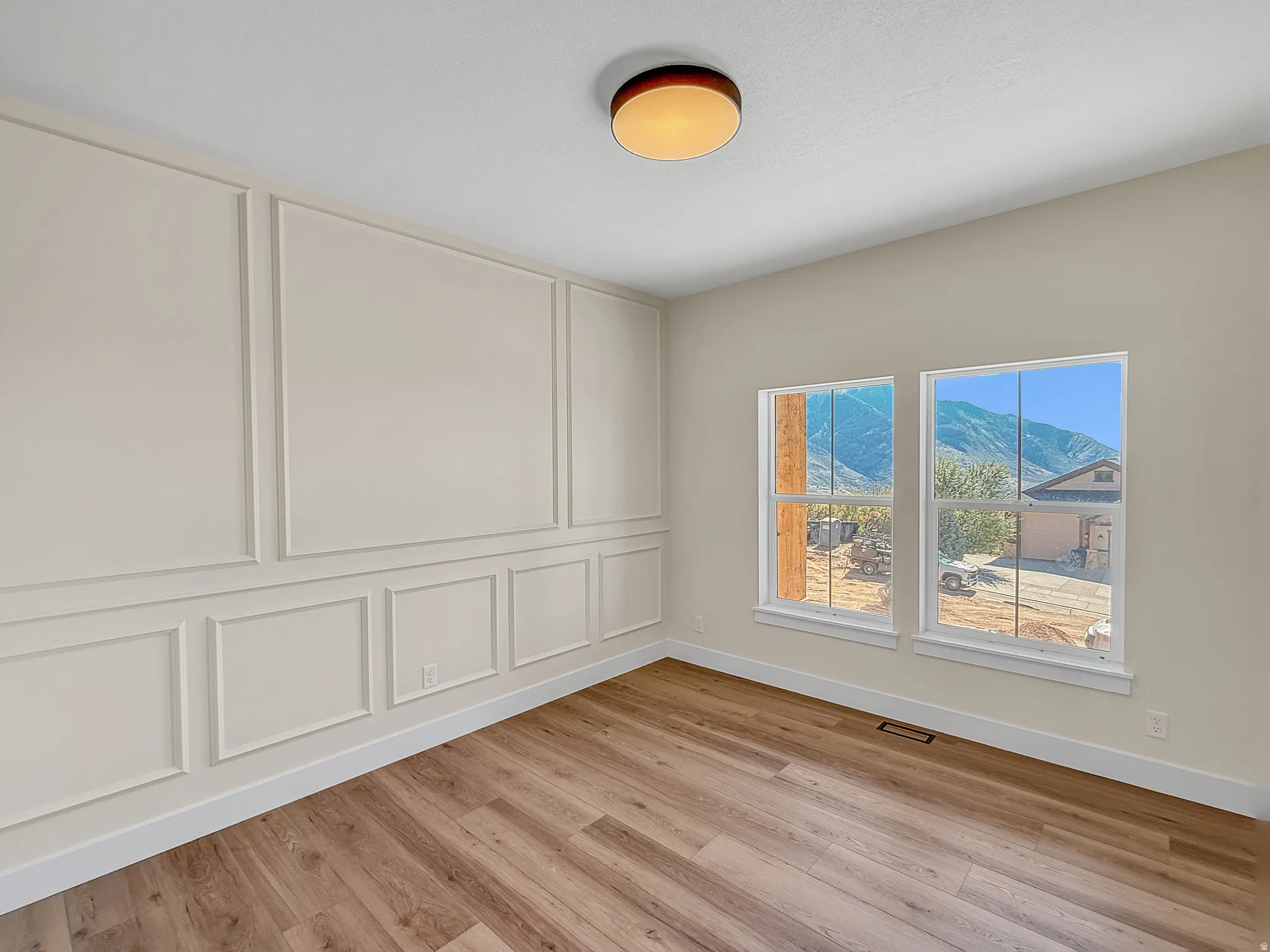 Spare room with a decorative wall, light wood finished floors, and a mountain view