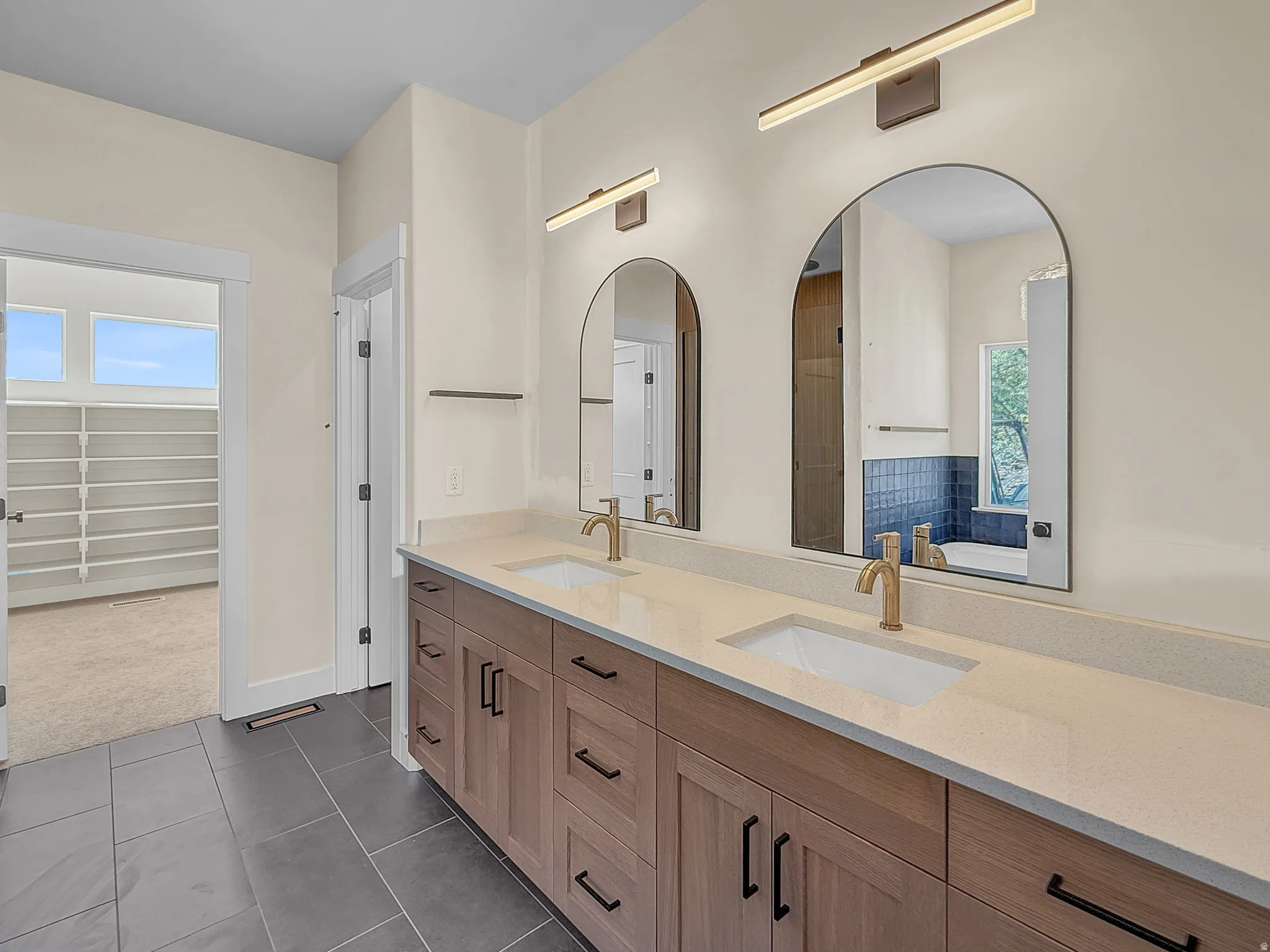 Full bath with plenty of natural light, double vanity, dark tile patterned flooring, and dark carpet