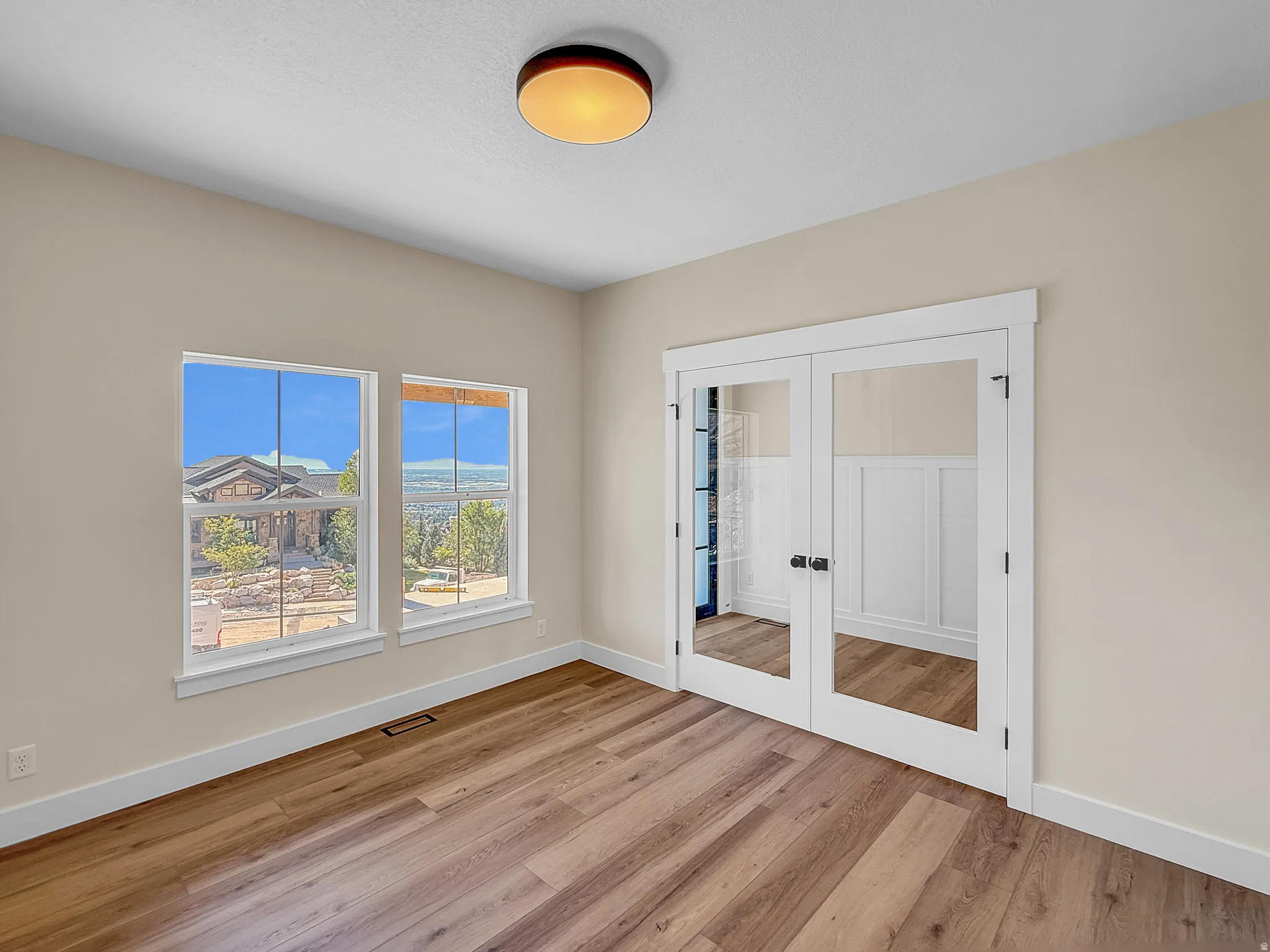 Unfurnished bedroom featuring french doors, light wood finished floors, and a closet