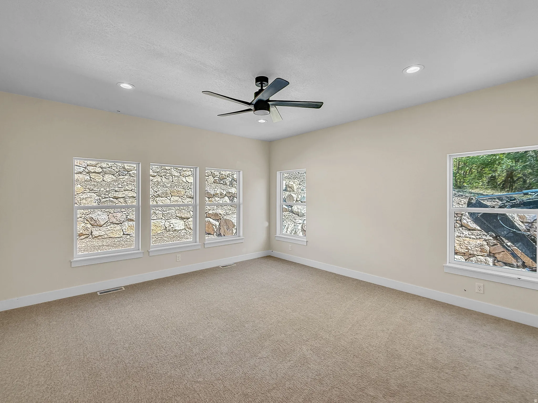 Empty room featuring light carpet, a ceiling fan, plenty of natural light, and recessed lighting