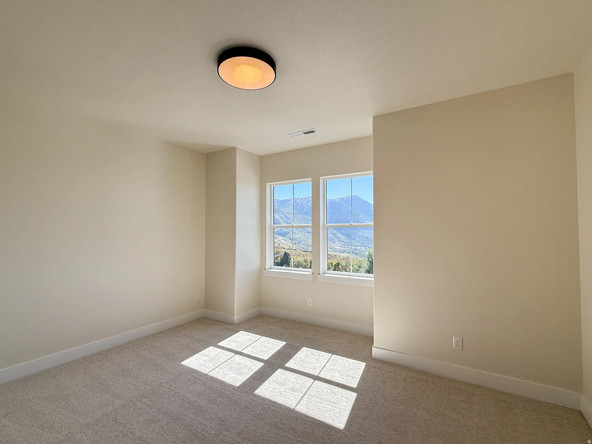 Spare room featuring a mountain view and light carpet