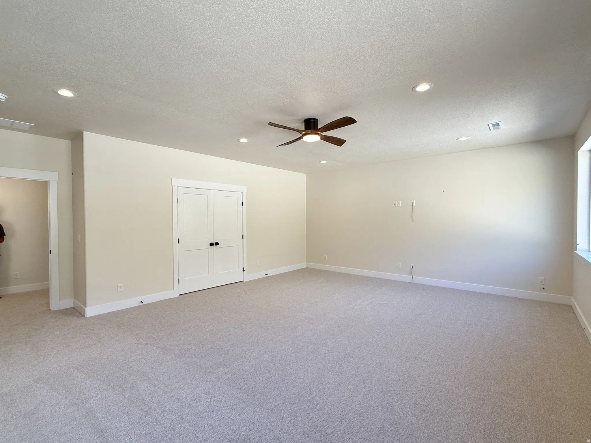 Unfurnished room featuring light carpet, ceiling fan, recessed lighting, and a textured ceiling