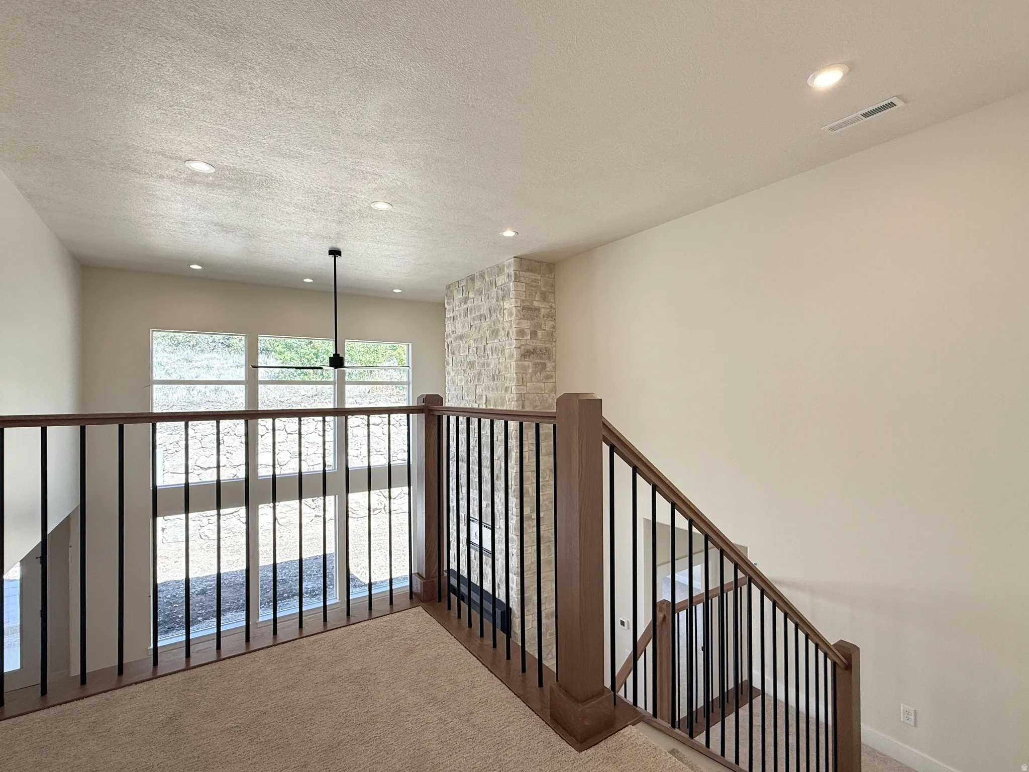 Corridor featuring carpet, a textured ceiling, recessed lighting, and an upstairs landing