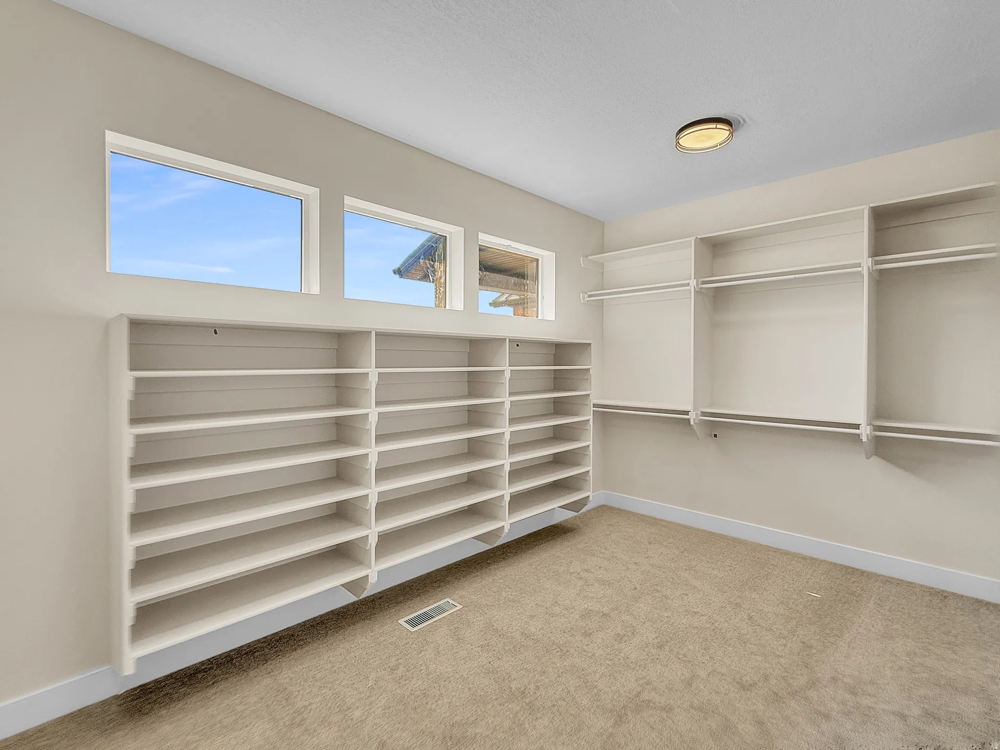 Walk in closet featuring light colored carpet