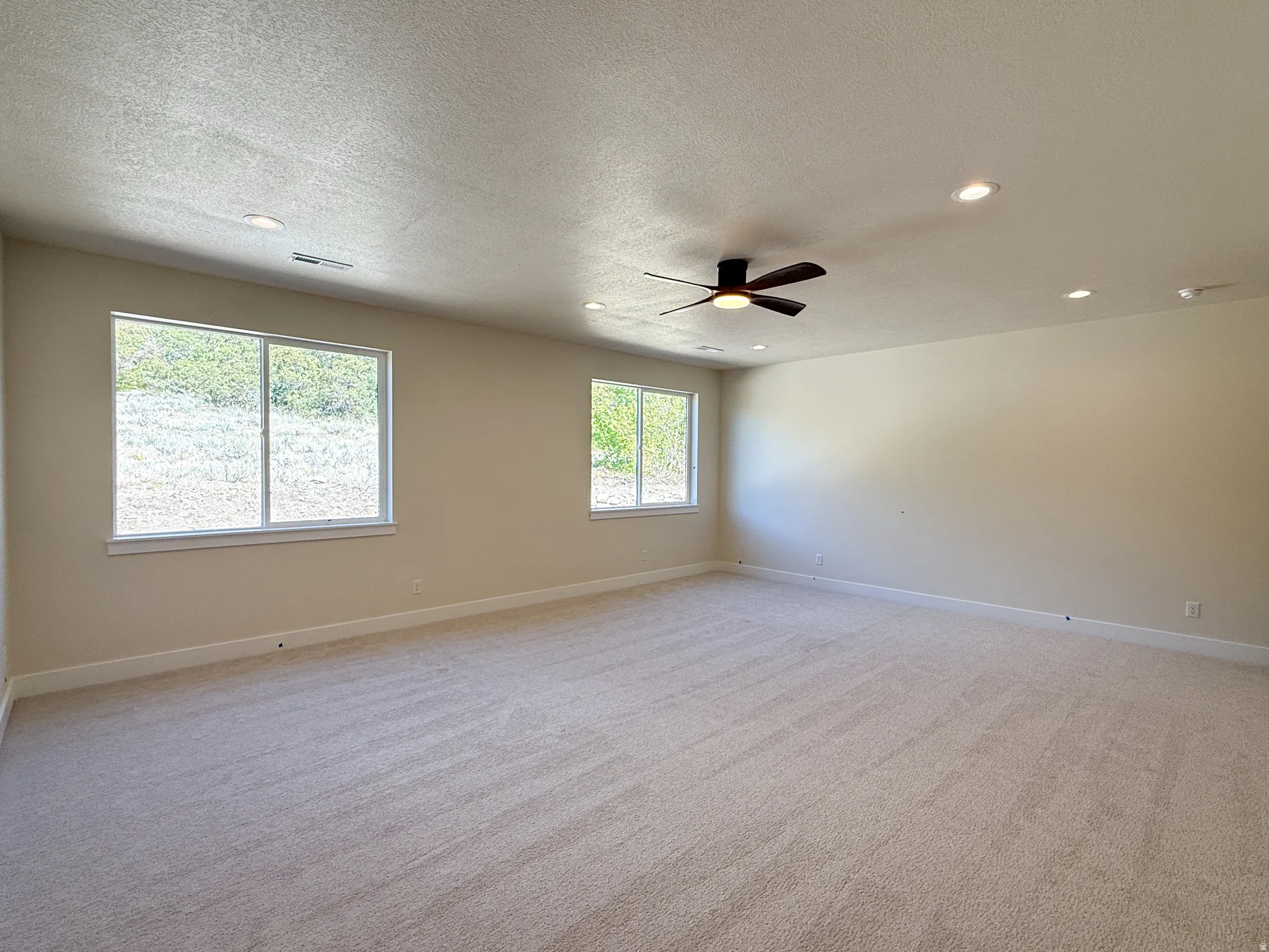 Unfurnished room with light carpet, recessed lighting, ceiling fan, and a textured ceiling