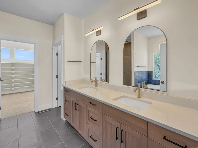 Full bath with plenty of natural light, double vanity, dark tile patterned flooring, and dark carpet