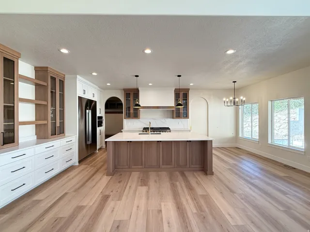 Kitchen with glass fronted cabinets, a spacious island, stainless steel built in fridge, dual tone cabinetry, and a textured ceiling