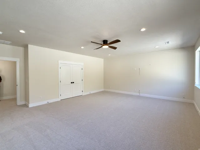 Unfurnished room featuring light carpet, ceiling fan, recessed lighting, and a textured ceiling