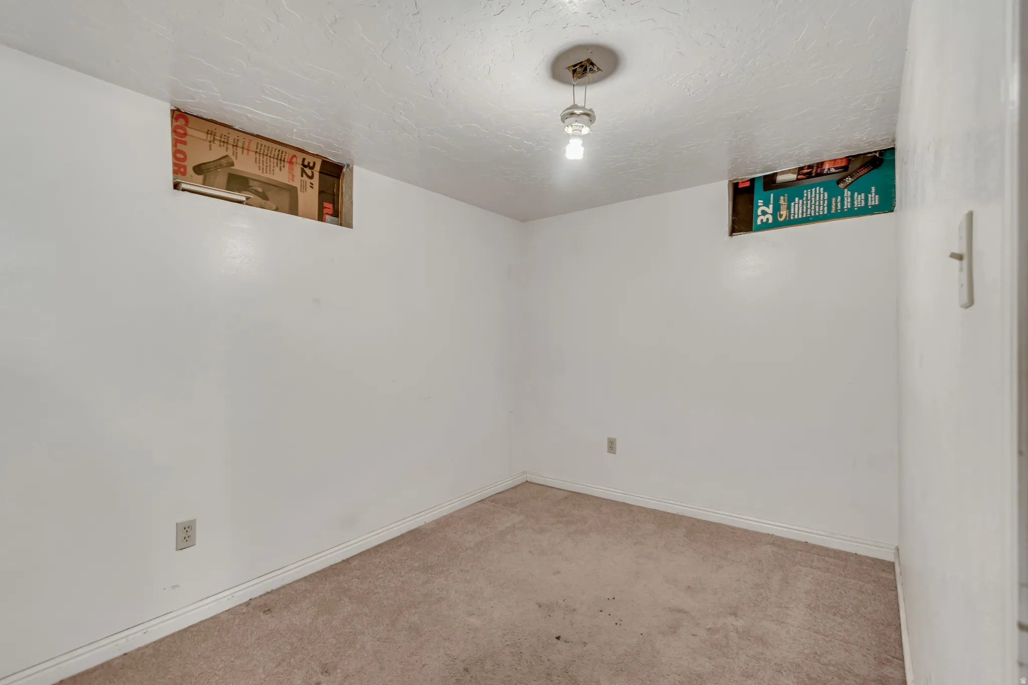 Carpeted empty room featuring a textured ceiling and baseboards