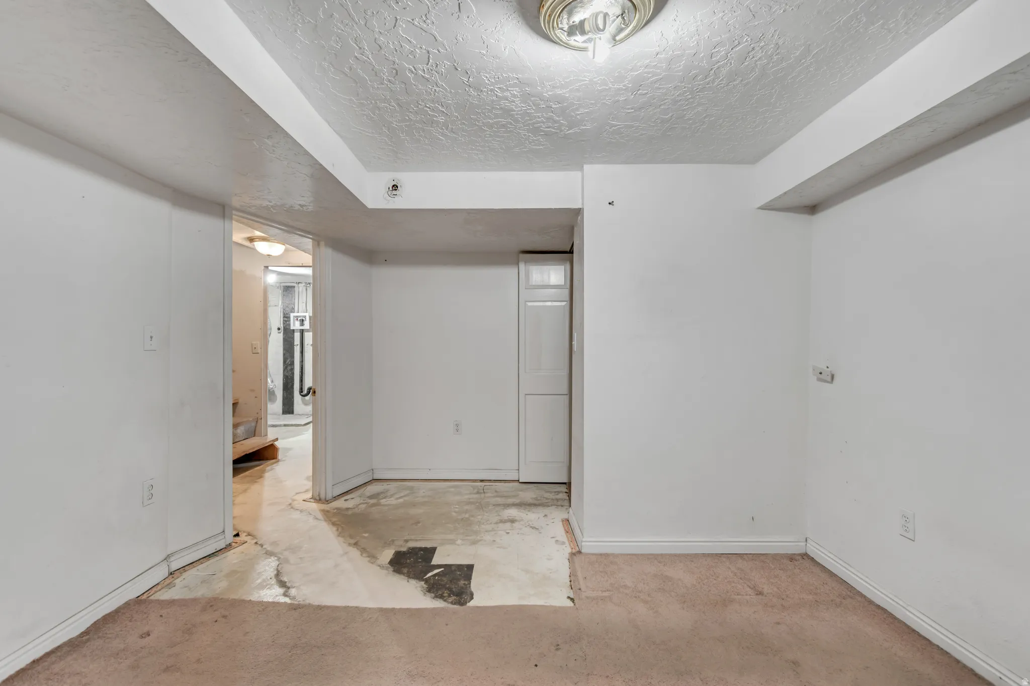 Spare room featuring a textured ceiling and unfinished concrete flooring