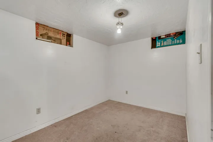 Carpeted empty room featuring a textured ceiling and baseboards