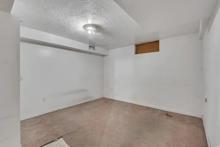 Empty room with a textured ceiling and baseboards