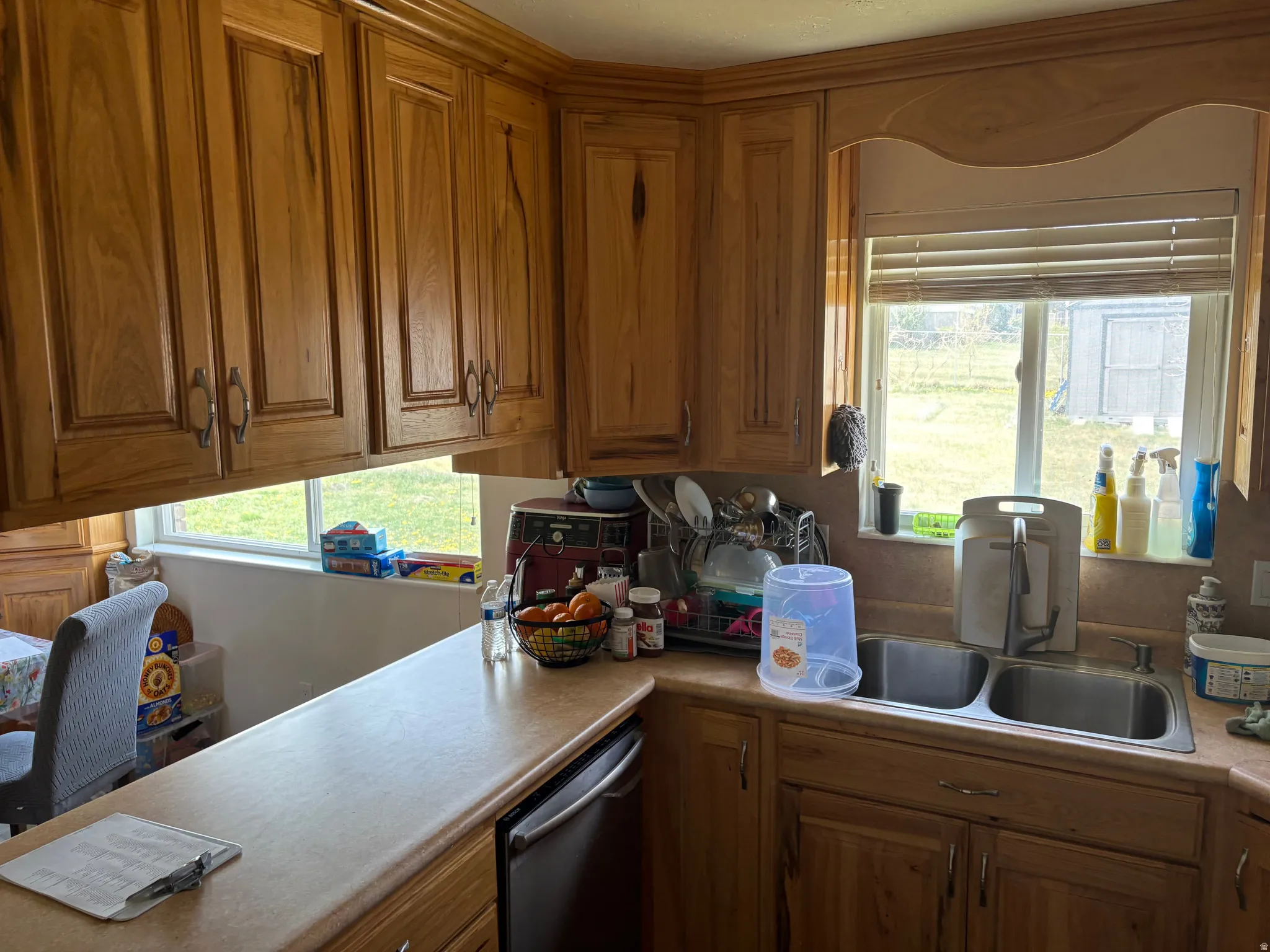 Kitchen with wood finish cabinetry, stainless steel dishwasher, and light countertops