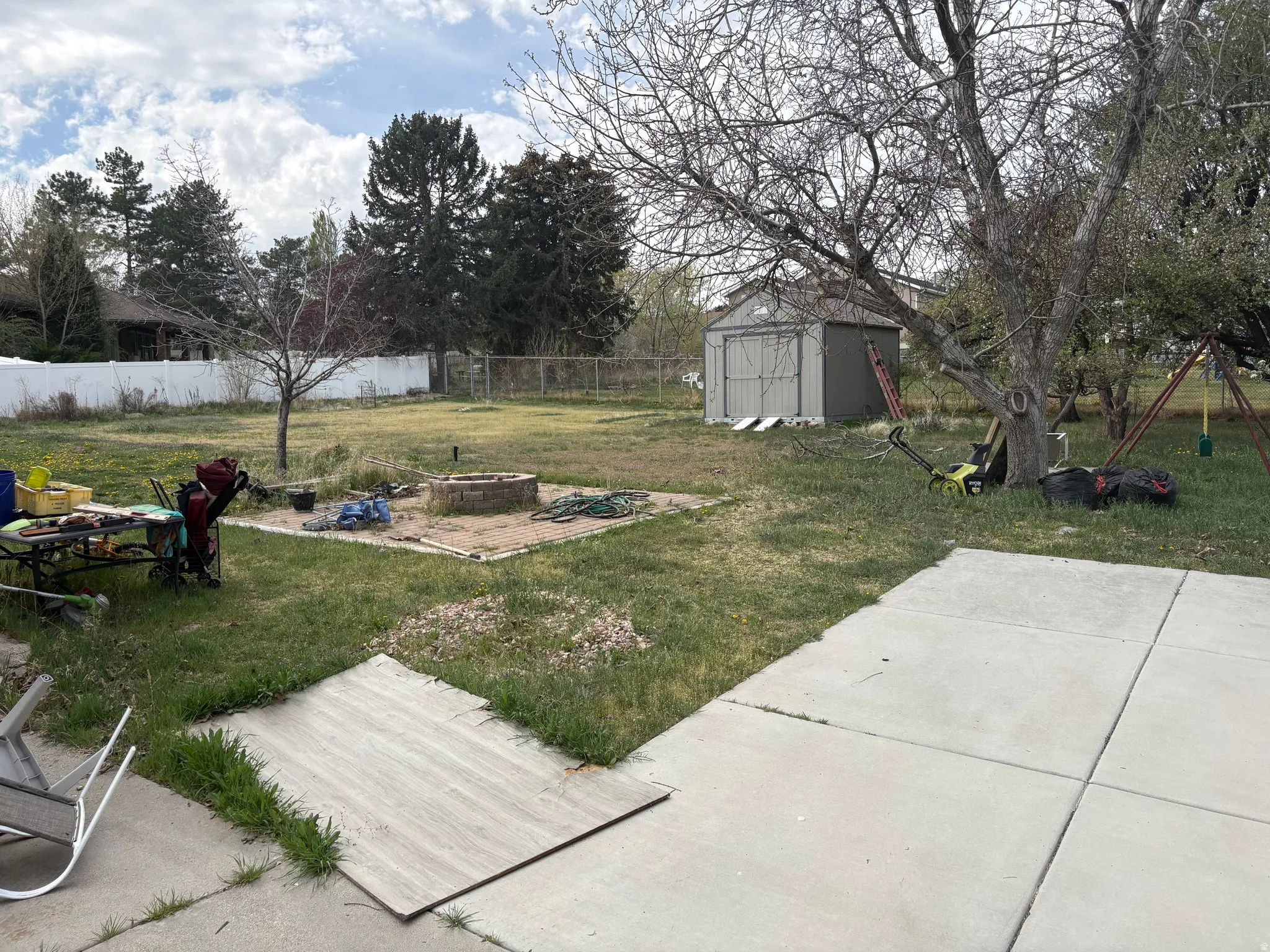 Fenced backyard featuring a fire pit, a patio area, and a storage unit