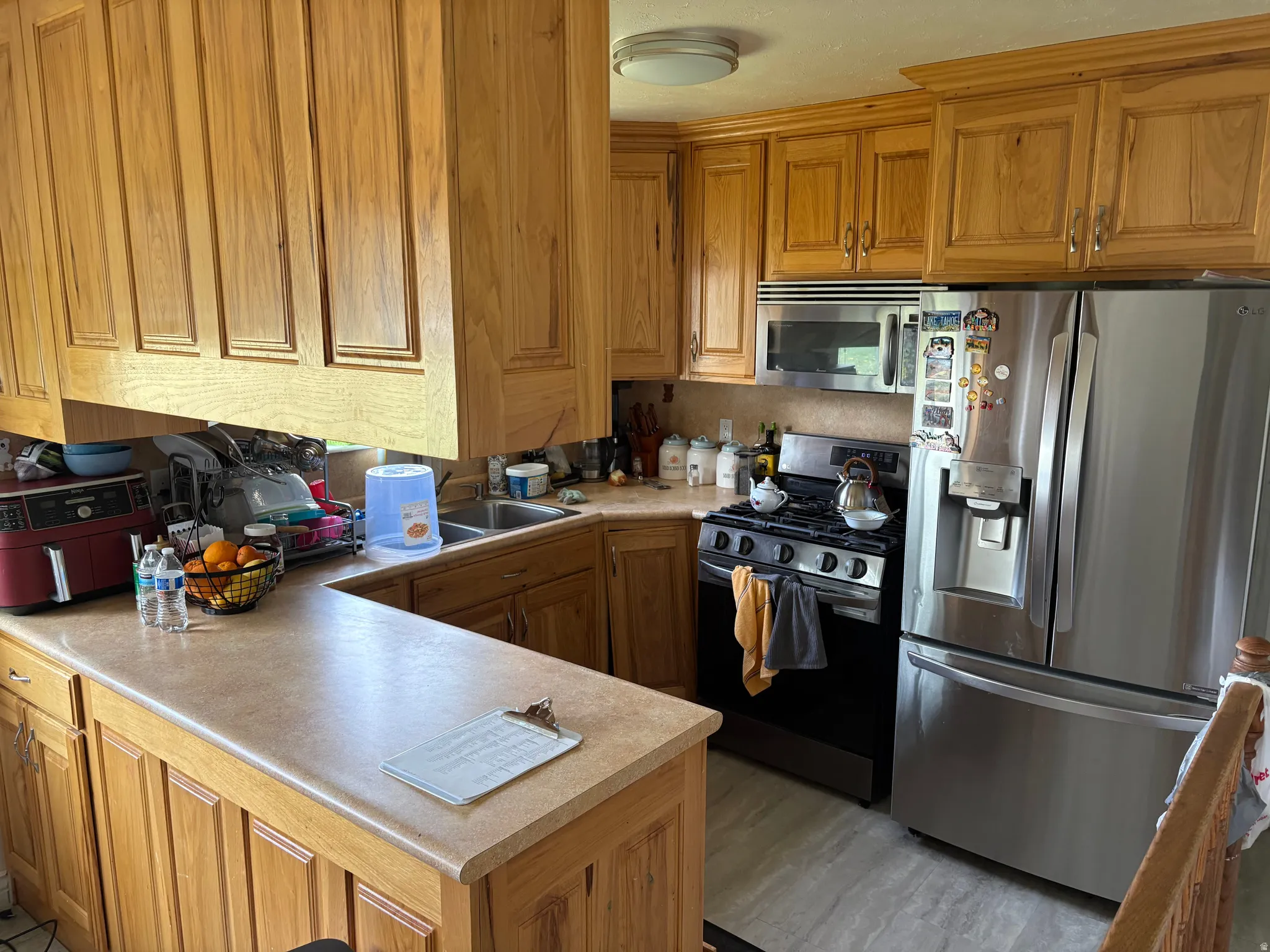 Kitchen featuring stainless steel appliances, wood finish cabinetry, light countertops, and light wood finished floors