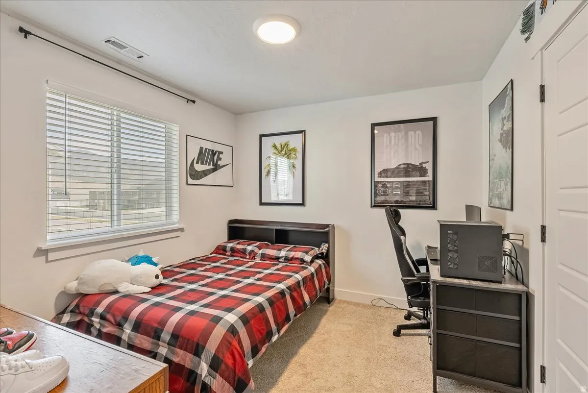 Bedroom with an office area and light carpet