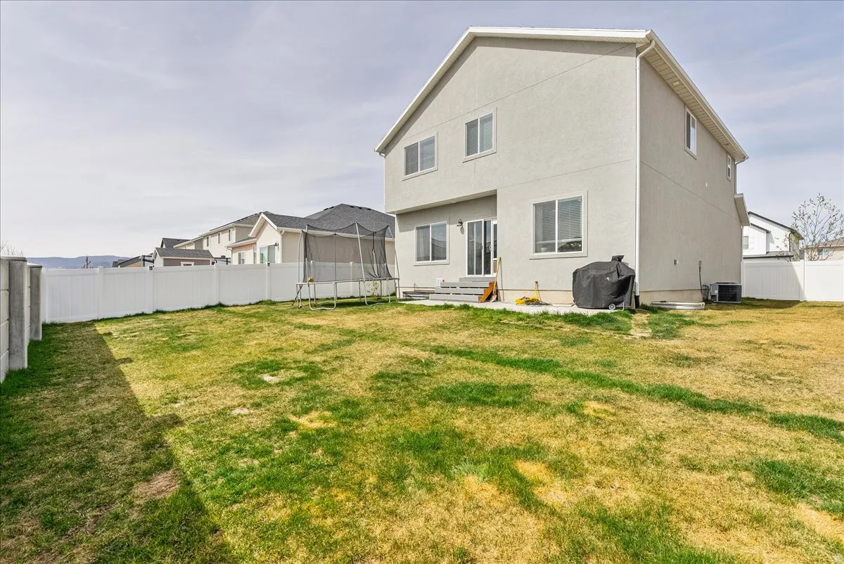 Back of house featuring a fenced backyard, a trampoline, and entry steps